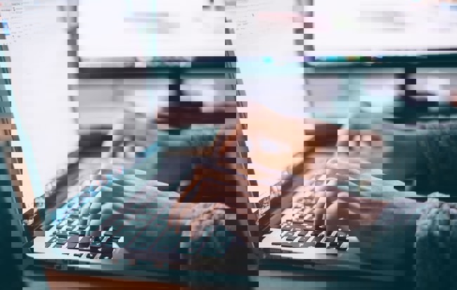 Närbild på händer som jobbar på en dator