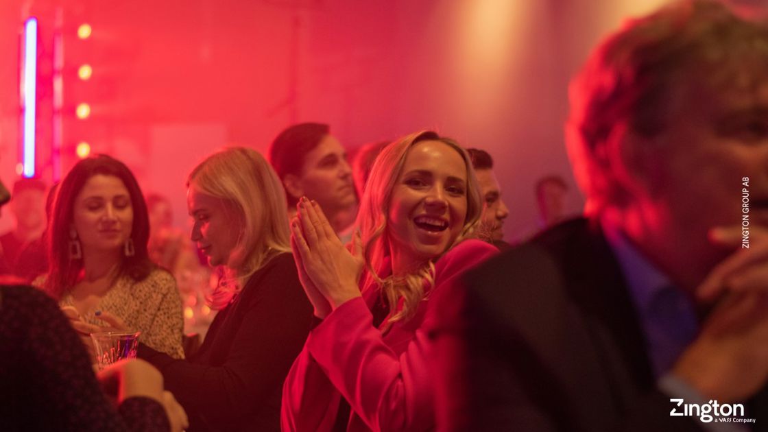 En kvinna bland massa andra människor dansar i ett disko med röd färgat tema.