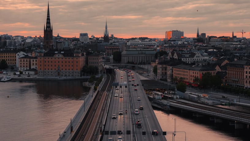 Flygfoto i skymningen över en bro i Stockholm med bilar på.