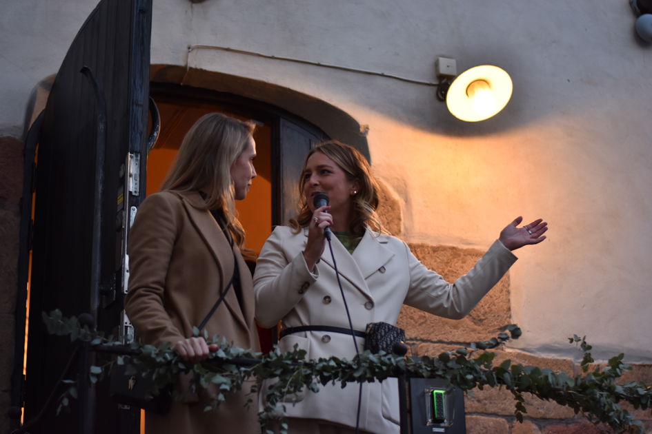 Två kvinnor står utomhus och pratar i en mikrofon.