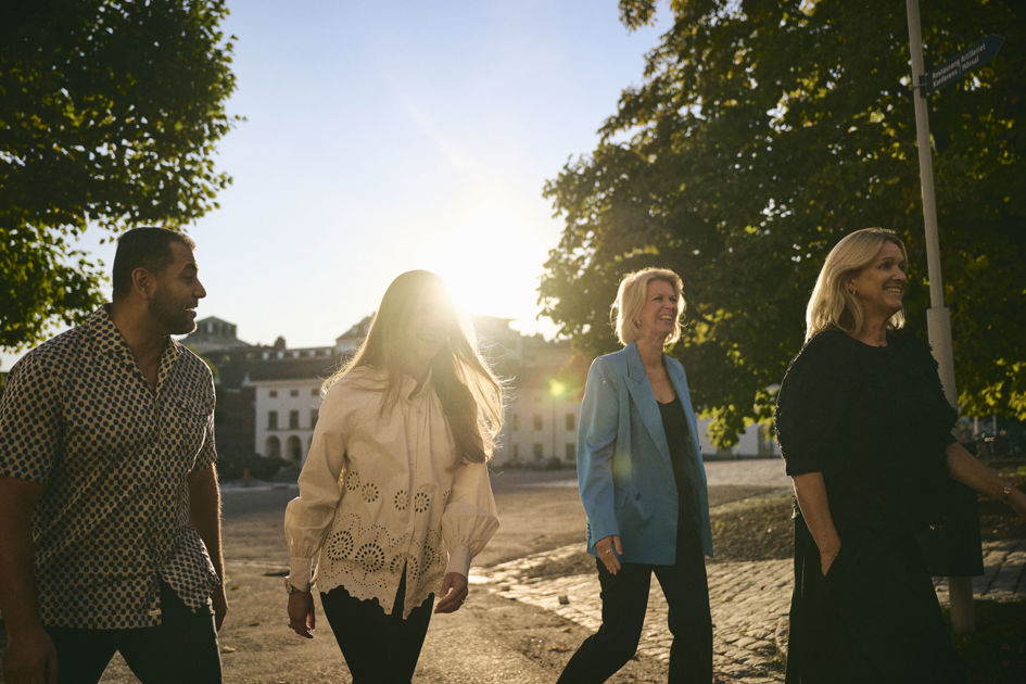 En grupp människor som vistas utomhus med solen som skiner och ett slott i bakgrunden.