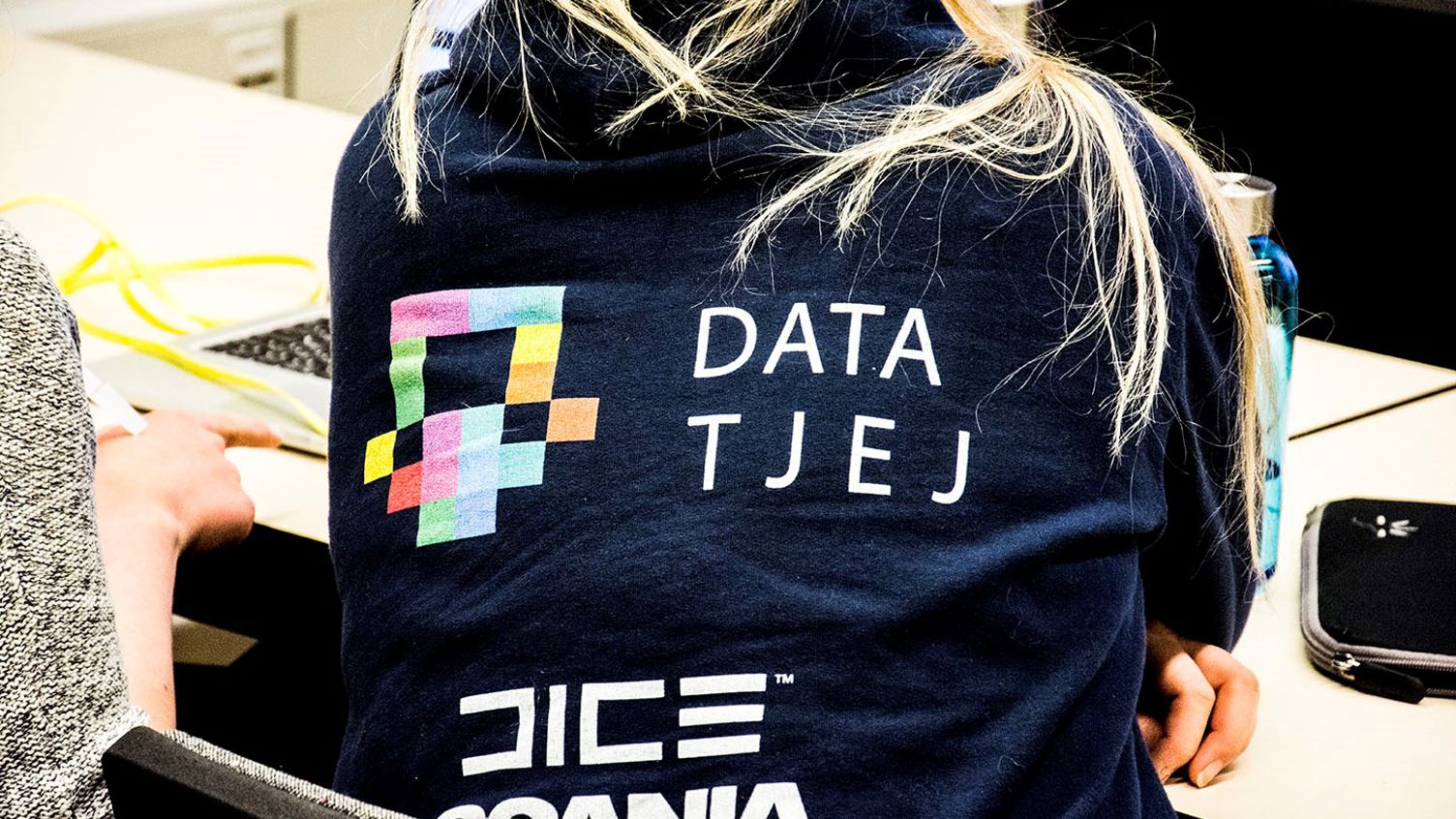 Ryggtavla av person med blå tröja där det står Data Tjej i form av en logotyp.