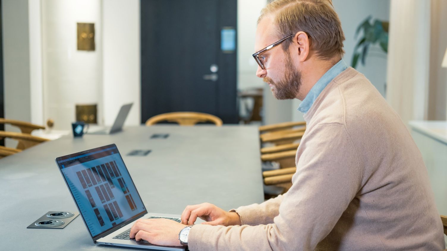 En man sitter vid ett bord med en bärbar dator.