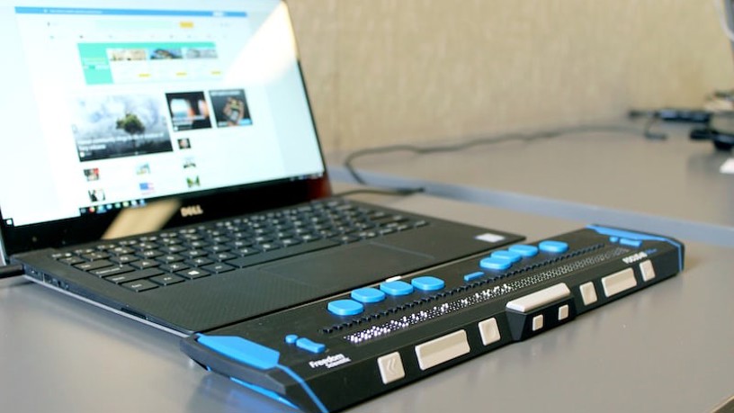Närbild av en bärbar dator med ett hjälpmedel för blindskrift framför.
