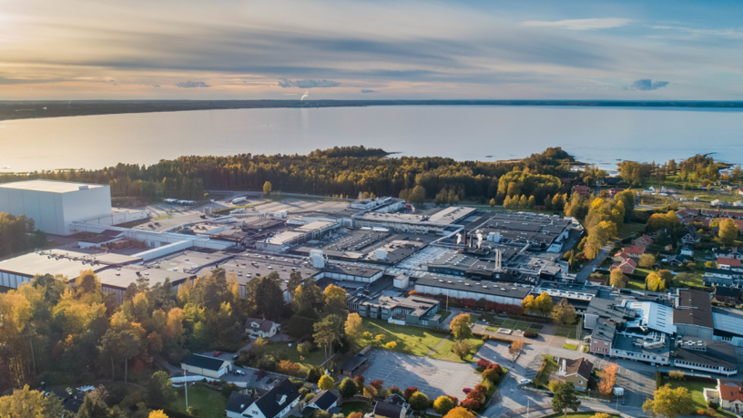 Flygfoto över ett industriområde med Vänern i bakgrunden.