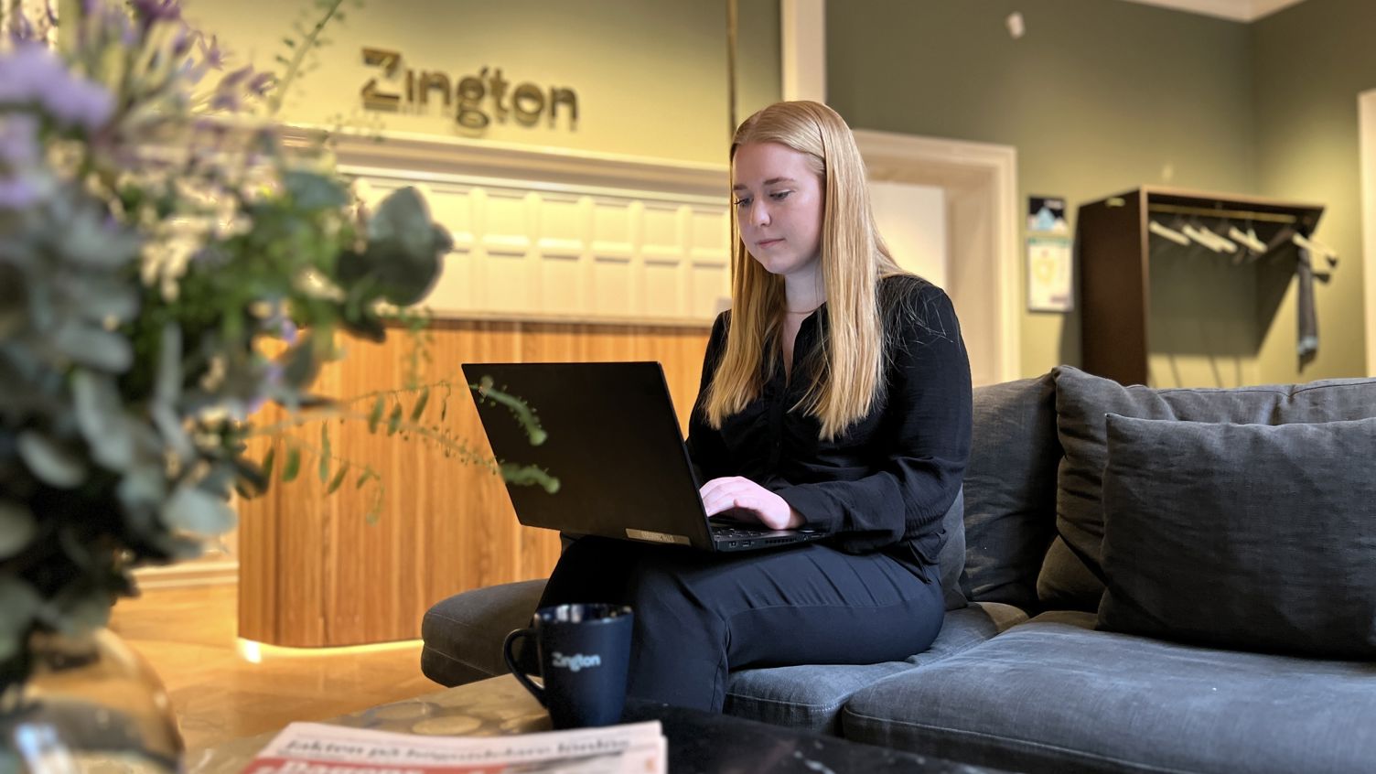 Kvinna som arbetar för Zington jobbar på soffan nära receptionen.