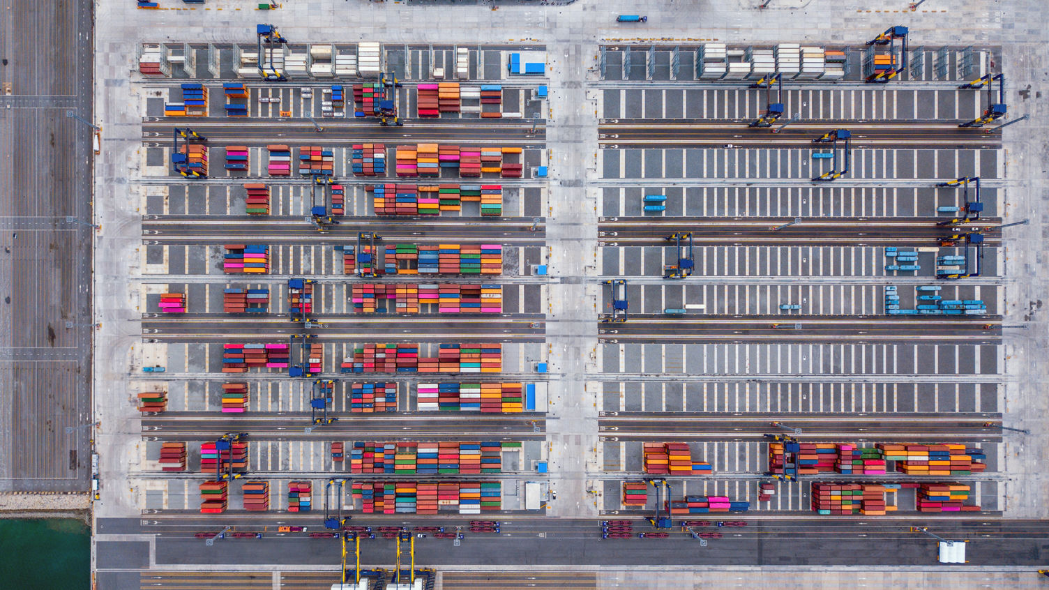 Flygfoto av många färgglada containers på en stor hamn.