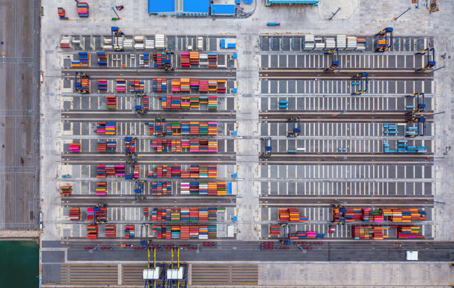 Flygfoto av många färgglada containrar på en stor lastplats.