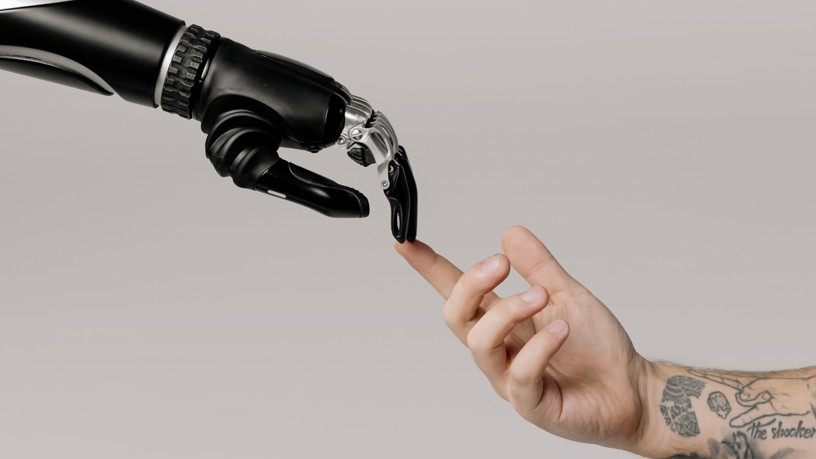 En robothand och en människohand möter varandra genom att röra vid varandras fingertoppar.