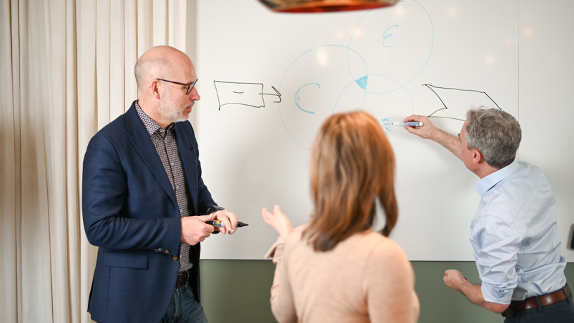 En grupp människor som arbetar runt en whiteboard.