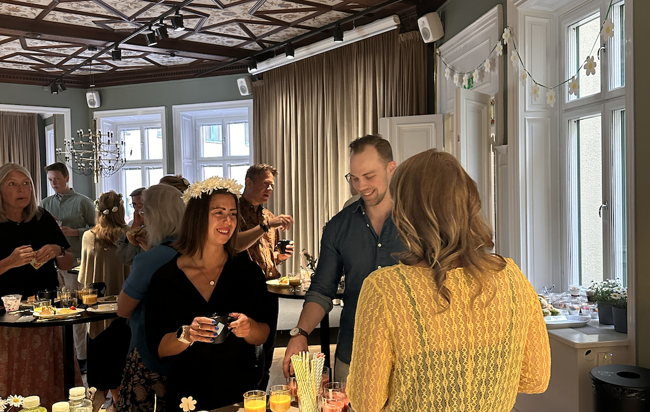 En grupp människor som står runt ett bord med frukt och drinkar.