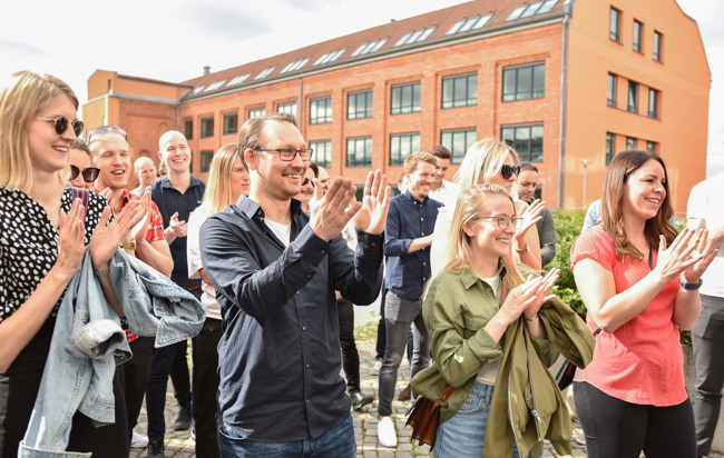 En grupp människor som klappar sina händer utomhus och ler.