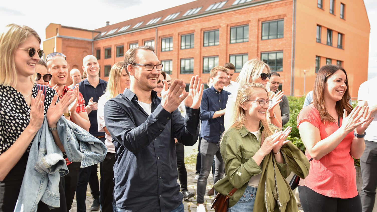 En grupp människor som klappar sina händer utomhus och ler.